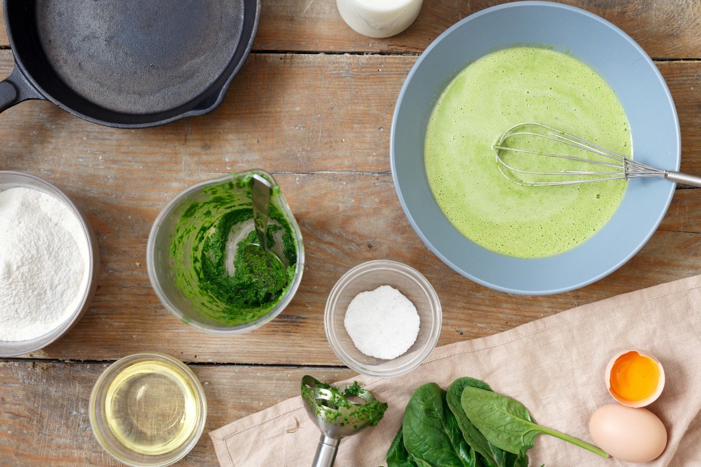 Set of raw ingredients for cooking healthy spinach pancakes on wooden table (dough, flour, eggs, oil, milk and spinach leaves) Gluten free spinach pancakes recipe